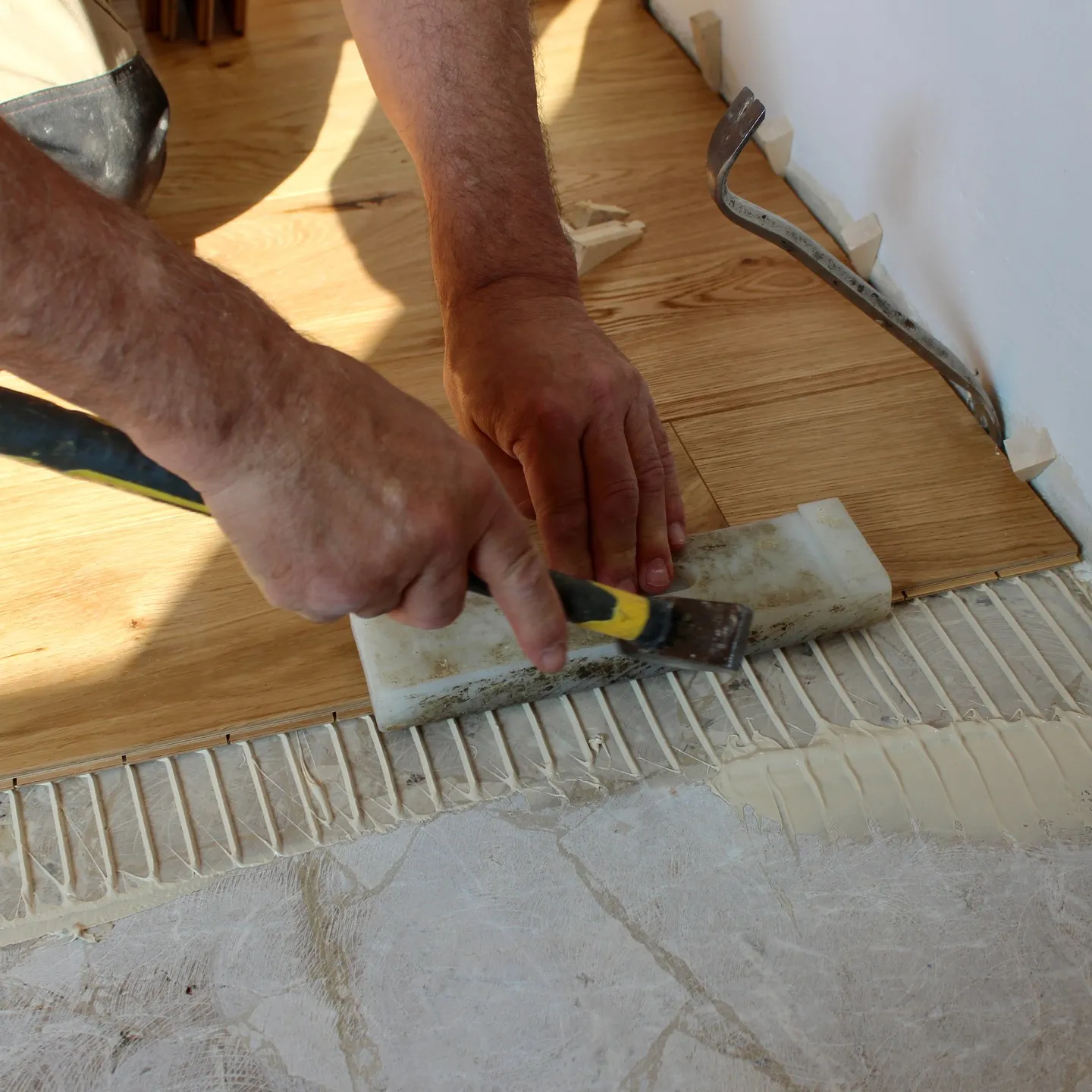 Le mani del posatore che allineano una doga di rovere sulla colla appena stesa — pubblicato il 27 maggio 2025